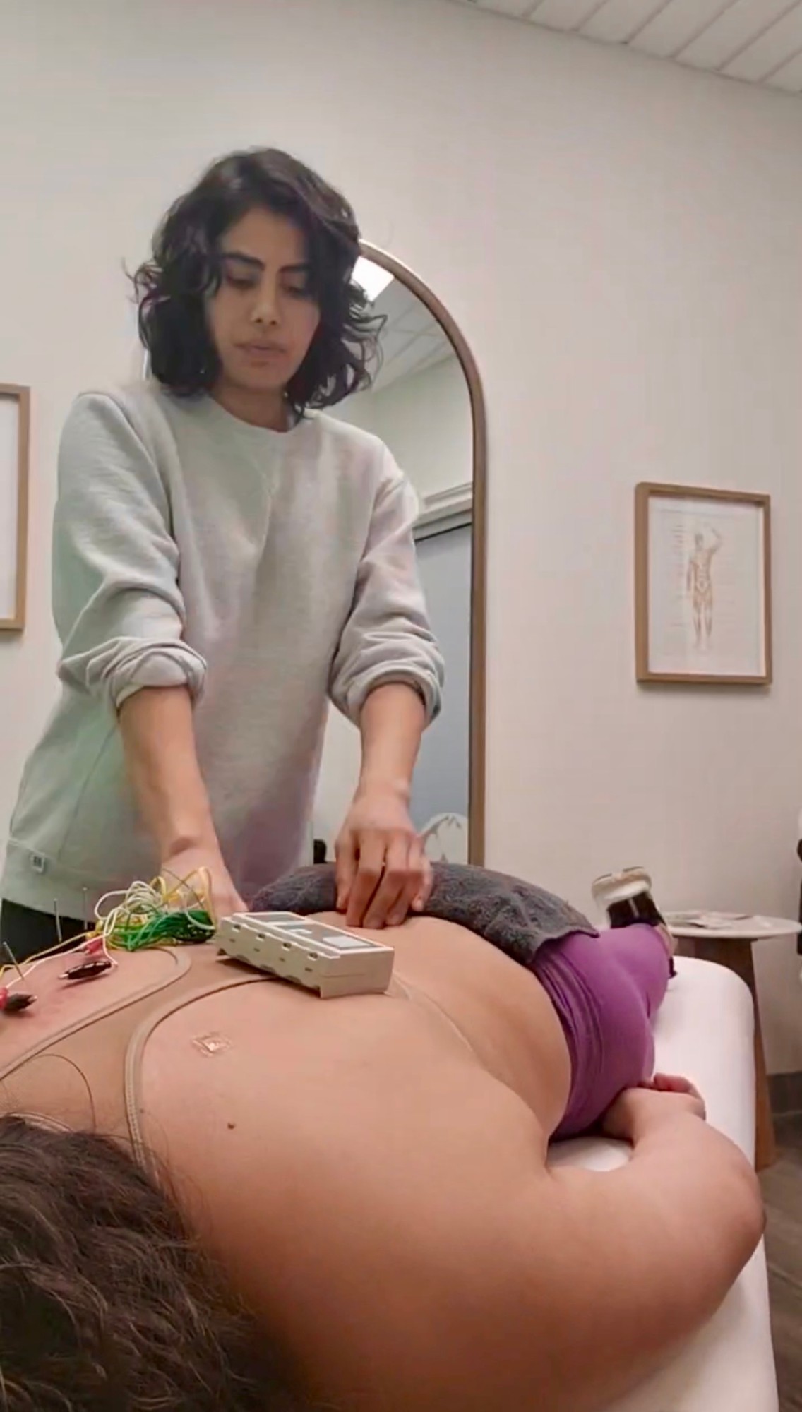 A practitioner giving hands-on back treatment alongside electro-acupuncture